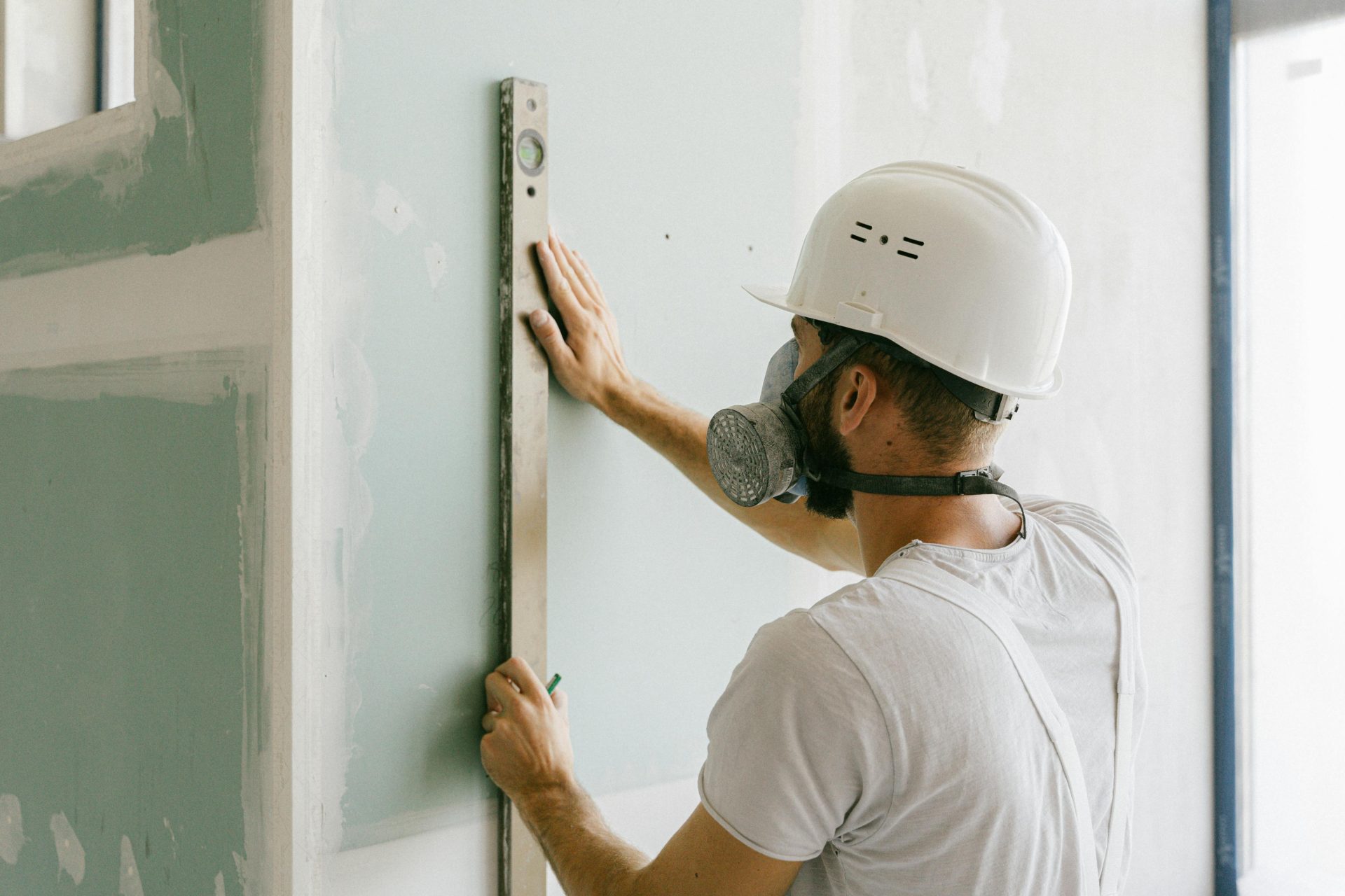 Ein Bauarbeiter verwendet eine Wasserwaage, um die Genauigkeit der Wand zu gewährleisten und stellt damit Präzision unter Beweis.